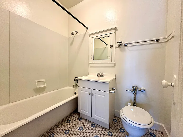 Bright bathroom with classic white fixtures, featuring a bathtub, elegant hexagonal tile flooring, and a stylish vanity with a mirrored cabinet. Bright bathroom with classic white fixtures, featuring a bathtub, elegant hexagonal tile flooring, and a styli