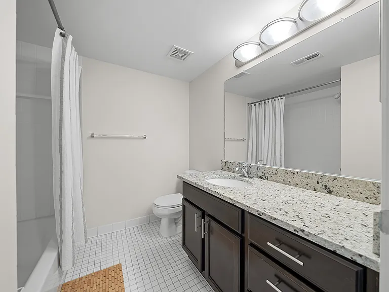 Modern bathroom with large vanity mirror and tub/shower at Lakeside Village Apartments in Clinton Township, MI