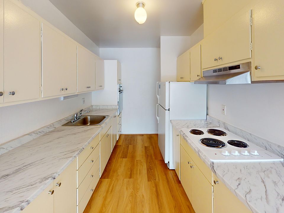 Kitchen with multiple cabinets, refrigerator, stove, range hood, and sink