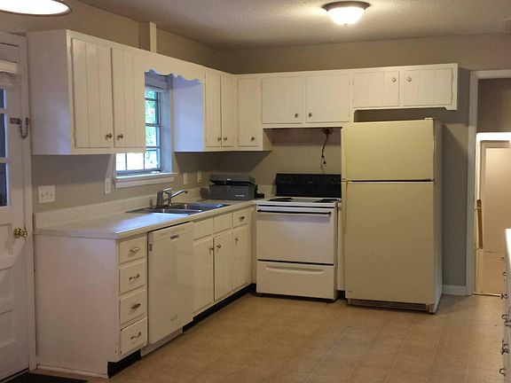 Kitchen has lots of counter space and storage, with a door to the back deck and fenced yard. Stairs lead down to laundry room and lower level (this photo shows old range)