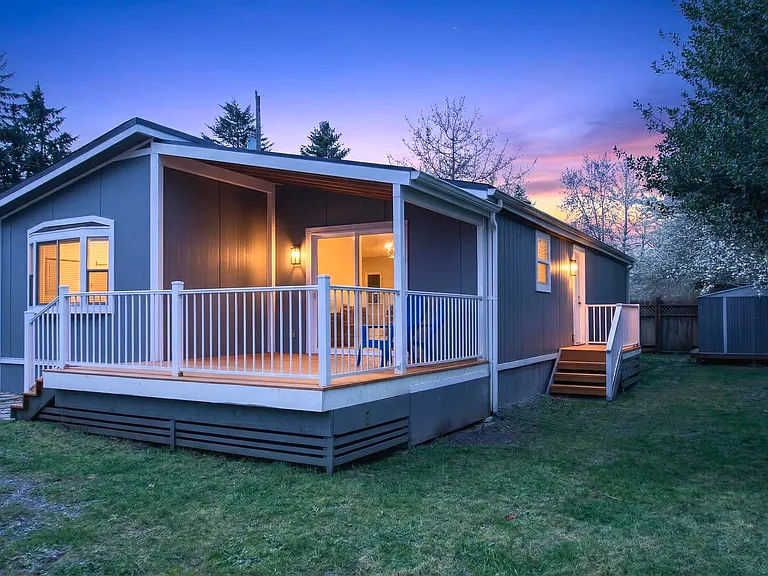 Front Exterior with Large Deck, Covered Porch, Storage Shed, and Twilight Sky