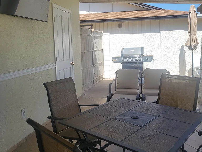 TV with streaming service, gas grill, and plenty of lawn furniture on back patio.