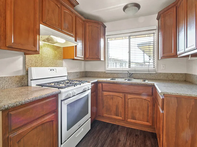 Kitchen with white gas stove, granite countertops, wood style kitchen cabinets
