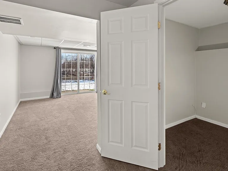 Bedroom with walk-in closet and sliding glass doors that exit to lawn and the Winooski River behind home.