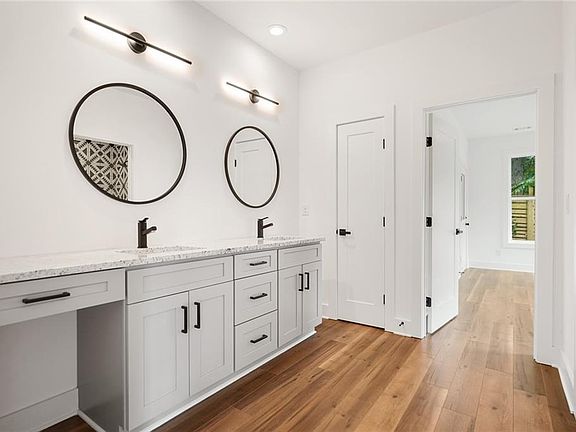 Downstairs washroom with dual sinks, built-in vanity, linen closet, and utility closet