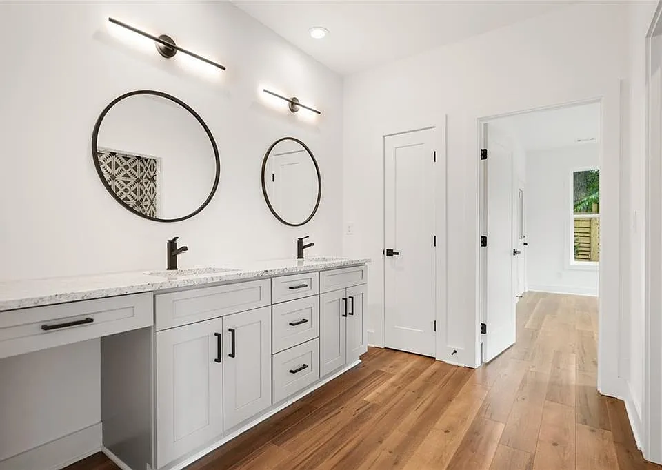 Downstairs washroom with dual sinks, built-in vanity, linen closet, and utility closet