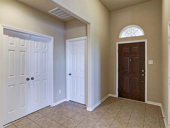 The spacious foyer has tile floors. The garage is the left of the entry and the secondary bedrooms to the right.