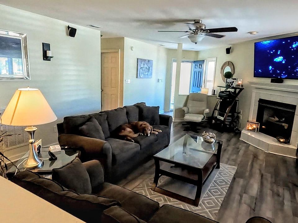 Large, open living room area with LVP and gas fireplace, wireless ceiling fan, in-wall surround sound, and TV mount over fireplace (included)