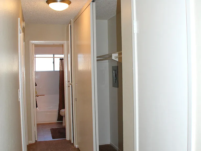 Carpeted bedroom hallway with closets and bathroom at Villa Pacific Apartments in Oceanside, California.