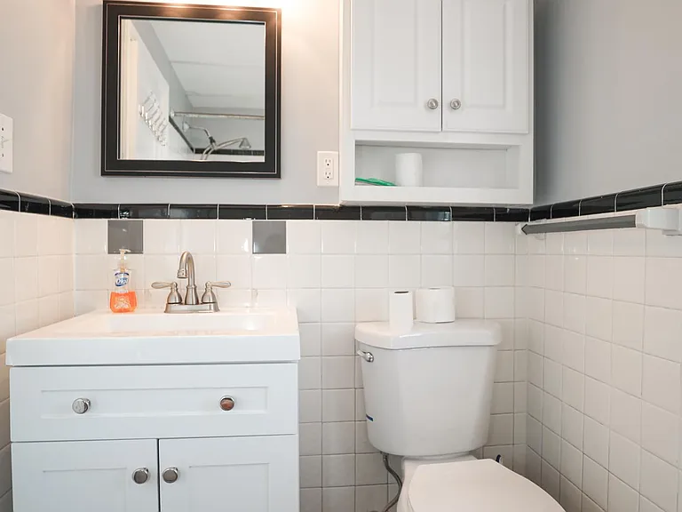Bathroom with vanity, toilet, and tiled accents.