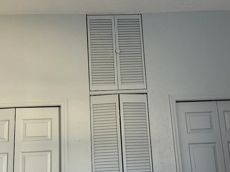 Closets in second bedroom with high ceiling and lights inside.
