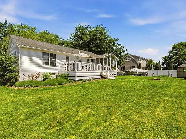 Large backyard with string lights, fire pit, shed, and beautiful gardens.