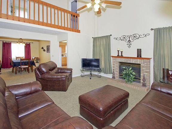 Living room with gas fireplace, vaulted ceilings, and ceiling fan