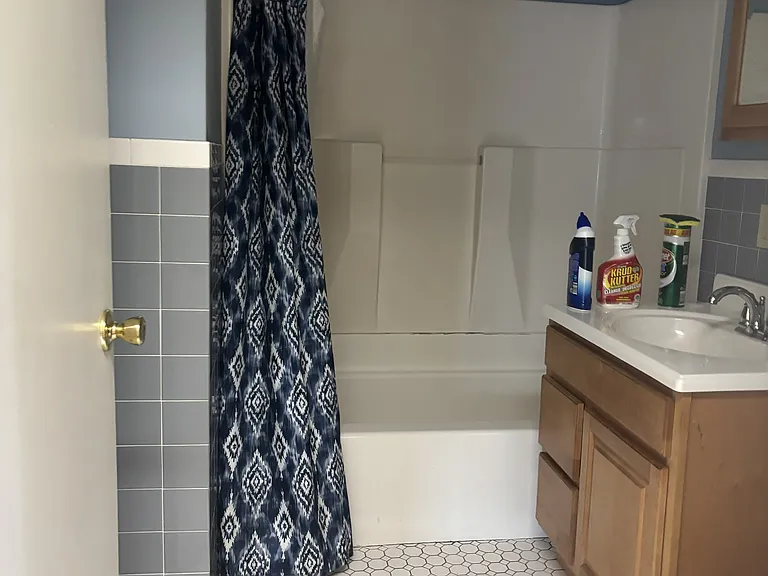 Tiled bathroom with tub/shower combination.