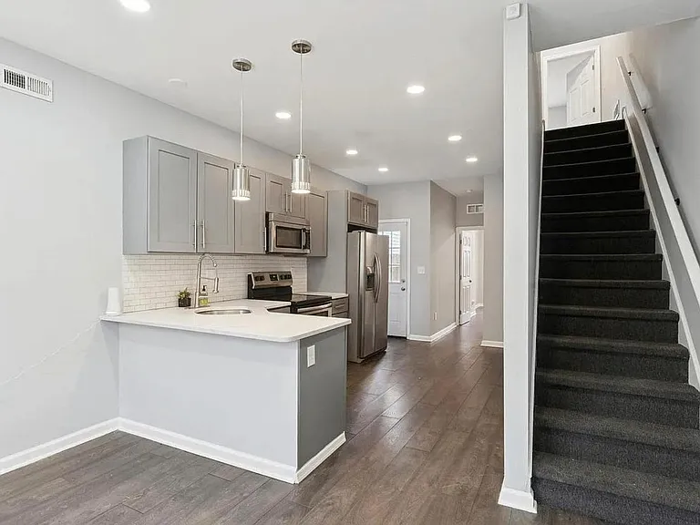 Open-concept kitchen with breakfast bar, pendant lighting, and stainless appliances plus ample cabinetry for storage.