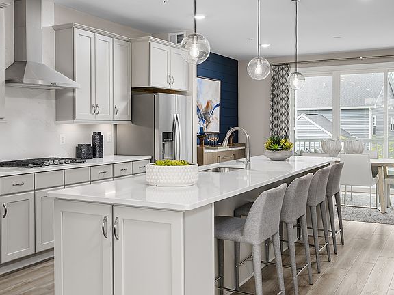 Island kitchen with white stone counters and large window slide doors in the Grable plan at the West