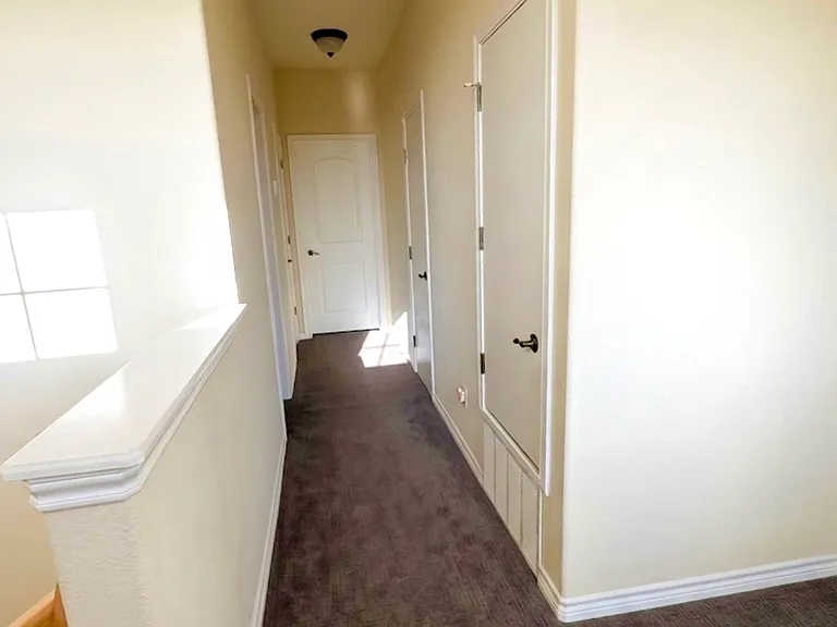 Bright upstairs carpeted hallway connecting both secondary bedrooms and secondary bath, offering a nook/flex space-perfect for a work desk, reading corner, or crafts area