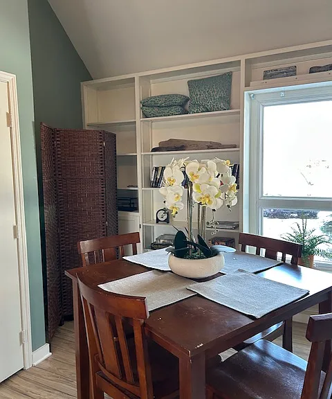 dining area, book shelves and portable bed for guests behind screen