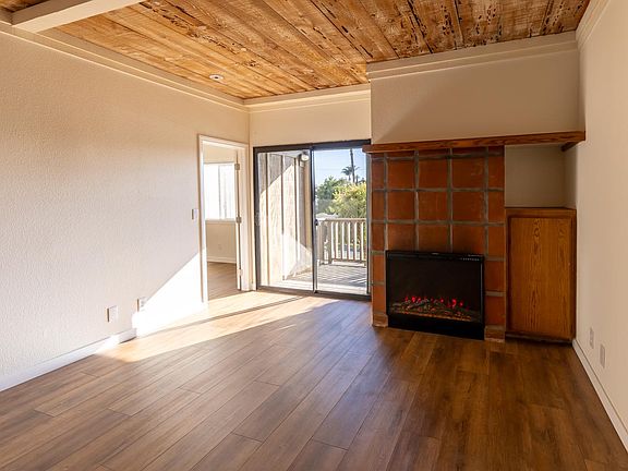 View from the living room out towards the back deck and patio. The original fireplace has been replaced with an electric insert
