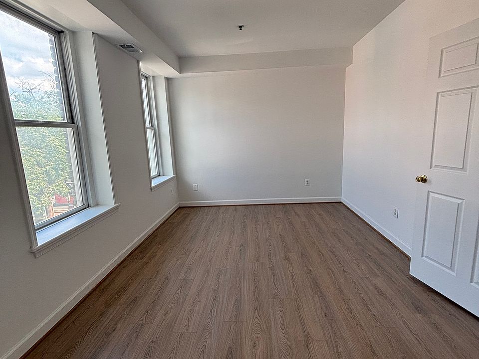 Bedroom with natural lighting from the windows, new hardwood floor, and fresh new paint.
