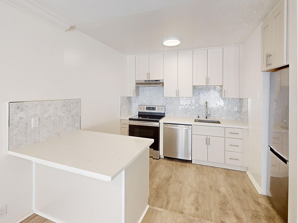 Kitchen with multiple cabinets, refrigerator, stove, range hood, and sink