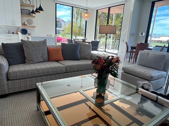 Living room area with bridge table and chairs and dining room in background