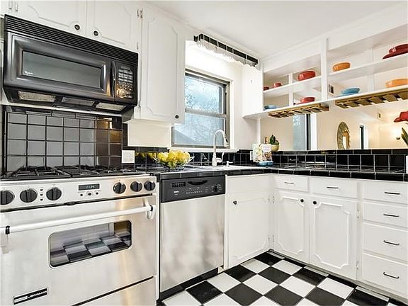 How cute is this black and white kitchen with large window at sink and stainless appliances.