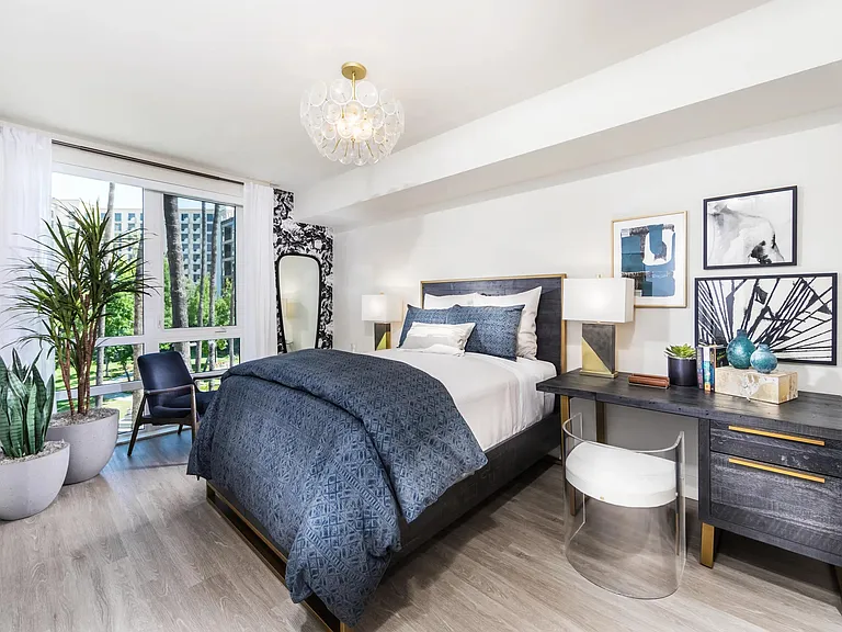 Spacious bedroom with refined finishes and oversized windows framing greenery.