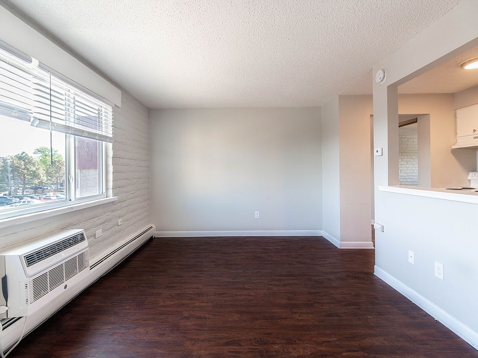 Bright and airy living area with large windows, sleek hardwood floors, and a cozy open kitchen design.