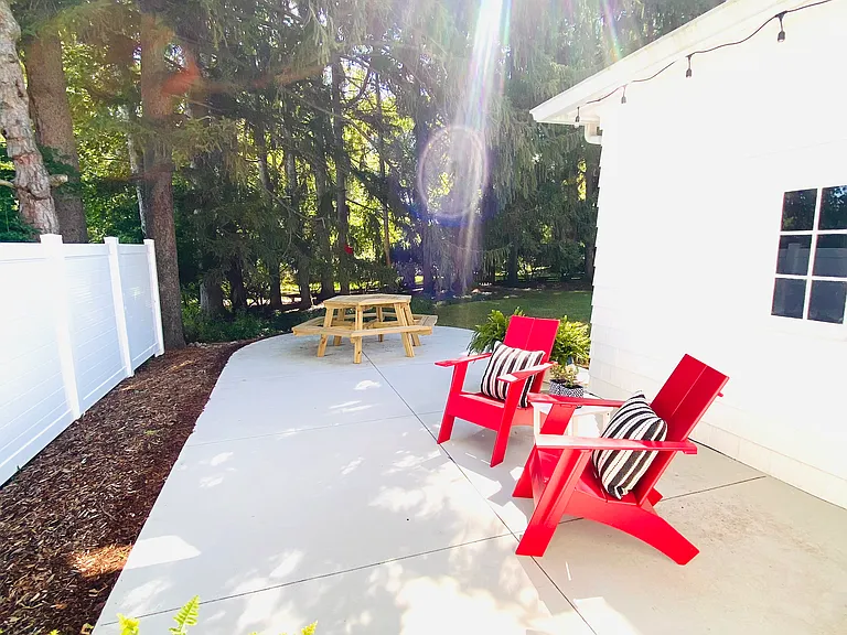 Enjoy your morning coffee in the comfortable Adirondack chairs or gather around the picnic table for outdoor dinners. A cozy bench sits beneath the overhang, illuminated by string lights, creating a warm ambiance for evenings outdoors.