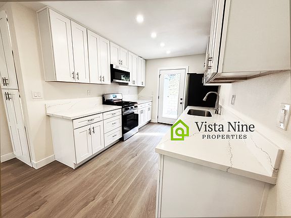 Another view of this gorgeous kitchen. Plenty of countertop space! Extra pantry cabinets on the left and door to the private yard space.