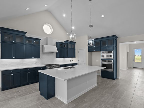 Kitchen features deep blue stacked cabinets with glass-front uppers