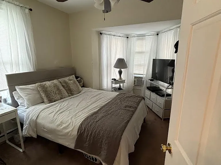 bedroom with lots of windows. ceiling fans are throughout the apartment