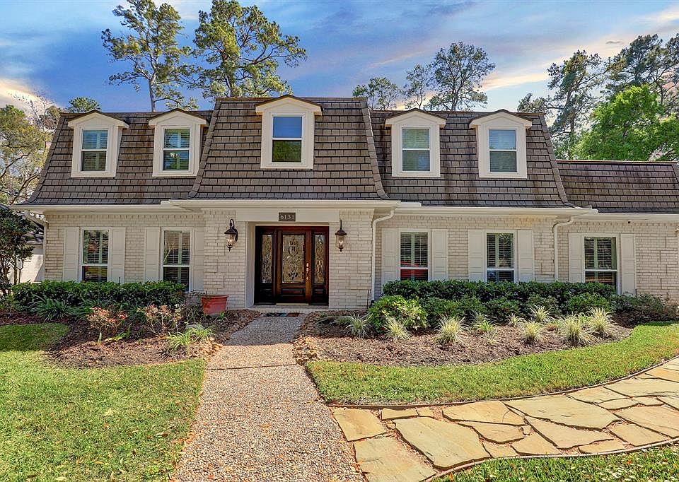 The stately faÃ§ade of 6131 Pebble Beach Drive showcasing new windows and enhanced by professional landscaping.