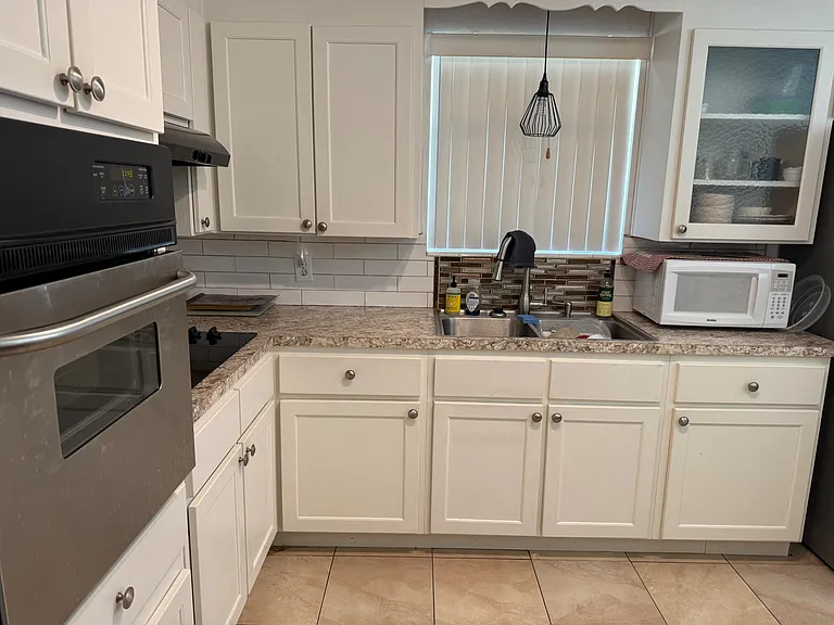 Efficient U-shaped kitchen with ample cabinetry, generous counter space, and a double-basin sink plus range and microwave.