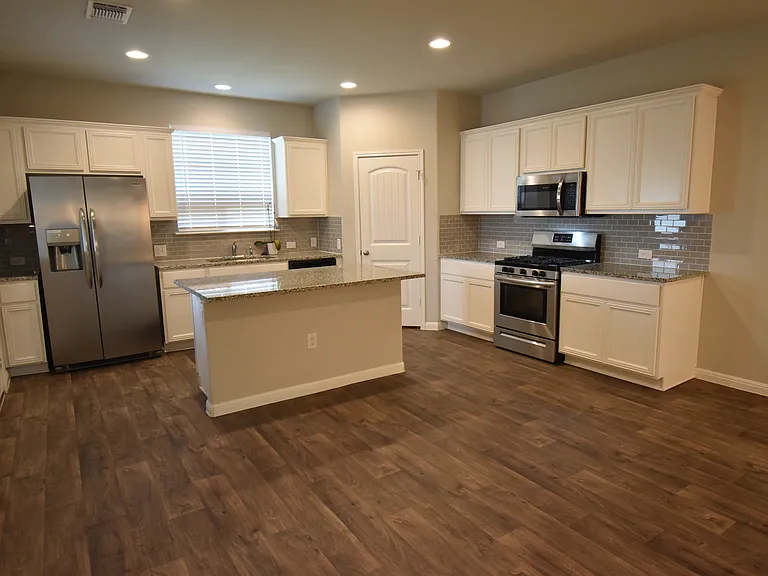Kitchen featuring a large island with stainless steel appliances and granite counters