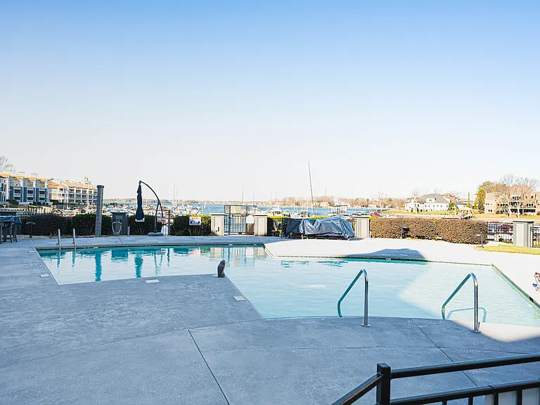 Community pool with plenty of lounge chairs, umbrellas, tables and chairs.
