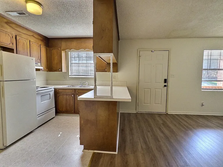 Eat-in kitchen with ample wood cabinetry, laminate counters, and a pass-through bar overlooking the main living area.