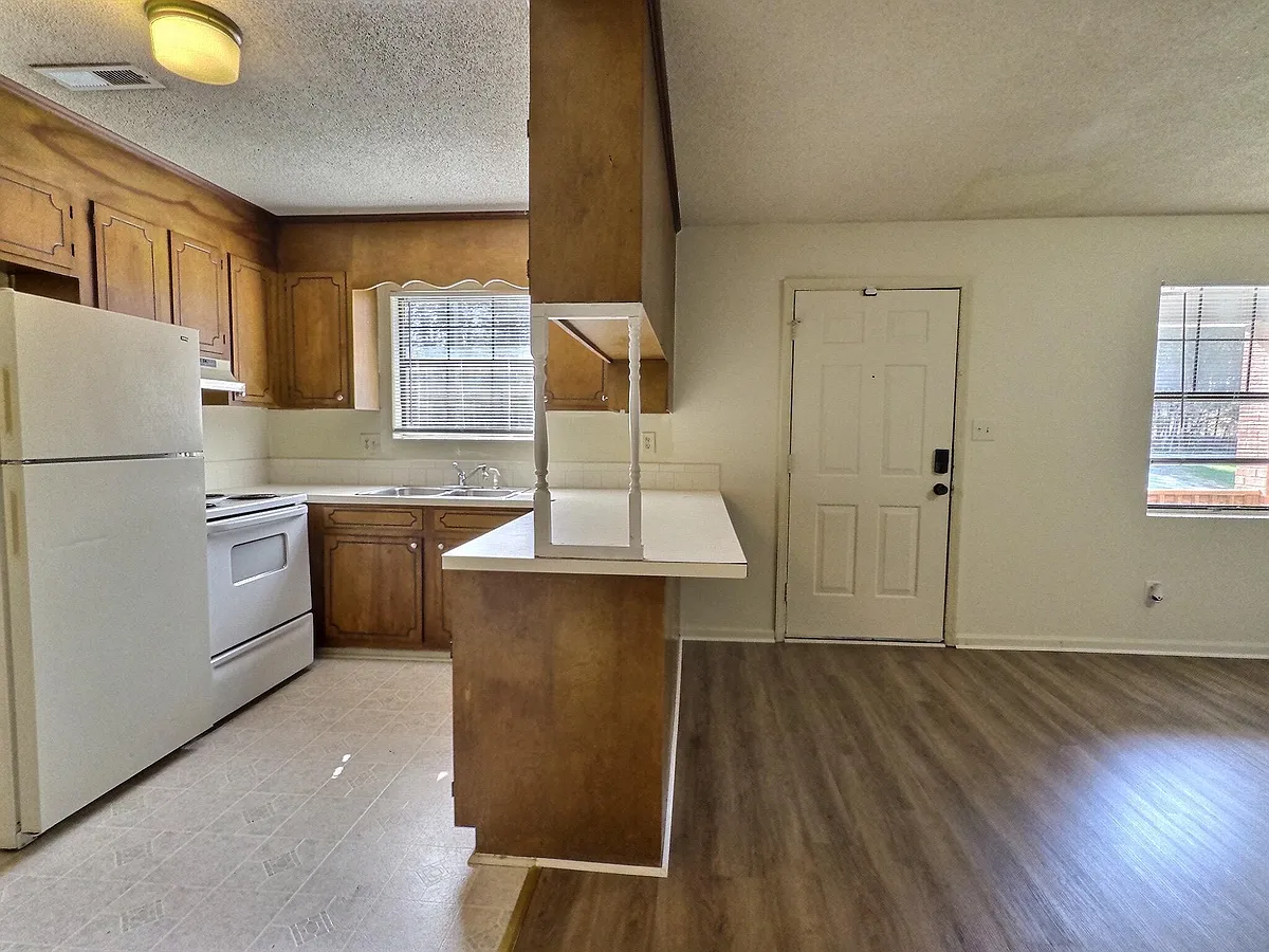 Eat-in kitchen with ample wood cabinetry, laminate counters, and a pass-through bar overlooking the main living area. - White Meadow Ln SE