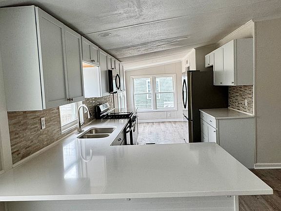 Updated kitchen with new cabinets, countertops, backsplash, and appliances. Kitchen features a countertop that allows for seating.