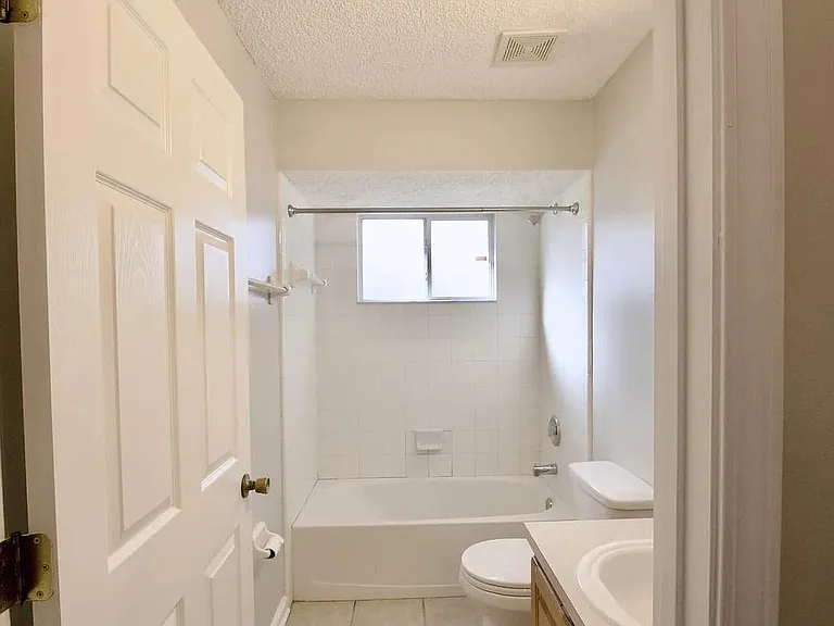 Full bathroom with tub/shower combo, tiled surround, and a privacy window for natural light and ventilation.