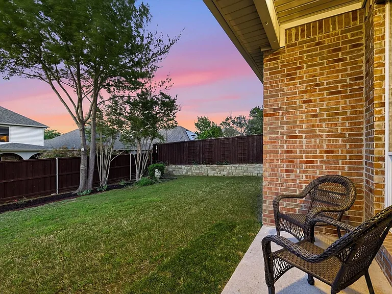 Private backyard featuring a manicured lawn, mature trees, and a wooden privacy fence