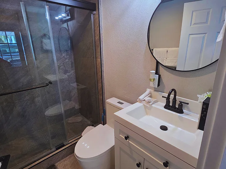 Modern full bathroom with a shower, toilet, sink, and mirror for your comfort.