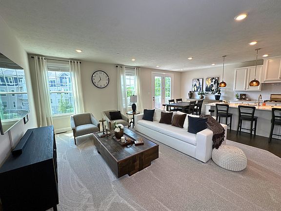 Bright and open main level featuring brand-new carpet, recessed lighting, and a seamless flow from the living room into the dining area and kitchen