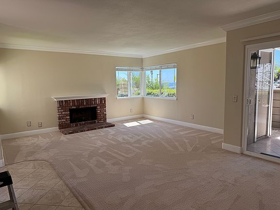 Living room view of fireplace, ocean view windows, patio door.