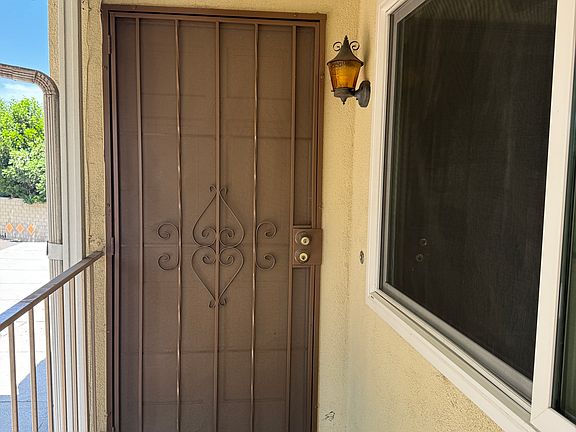 Front Door with security screen, light fixture, door bell, and 24 hour lighting.
