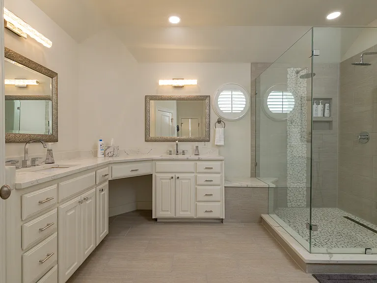 Luxurious master bathroom with a double vanity and glass shower.