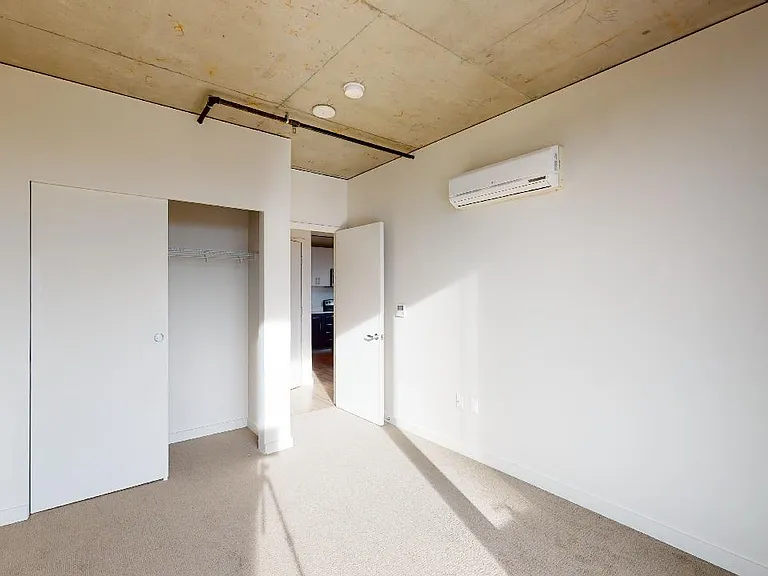 Spacious apartment bedroom with plush carpet flooring.