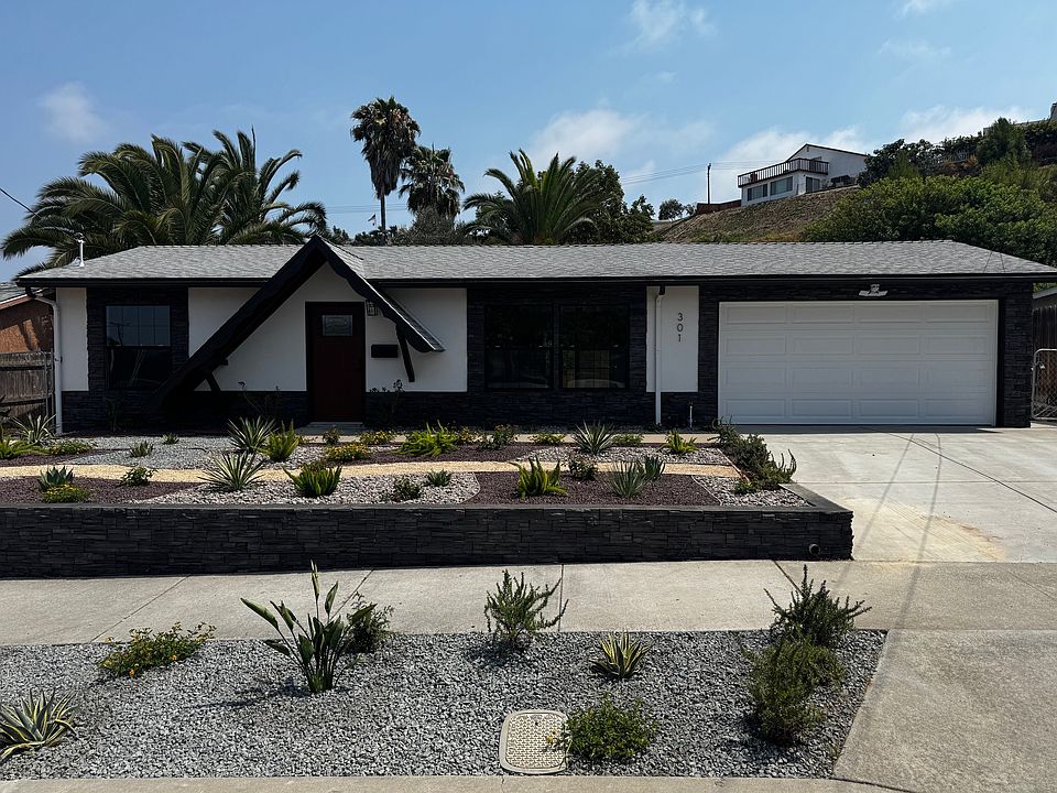 Newly-landscaped exterior front yard with drip irrigation and engineered stone siding.