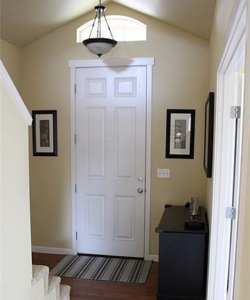 Vaulted entry with wood floor and transom window on the south side of the house for natural light.